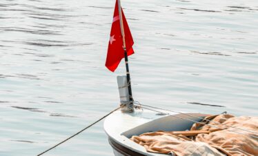 A peaceful boat with a Turkish flag floating on calm waters in Yalova, Türkiye.