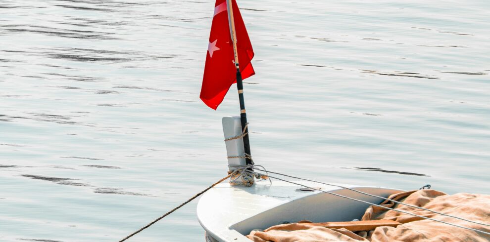 A peaceful boat with a Turkish flag floating on calm waters in Yalova, Türkiye.