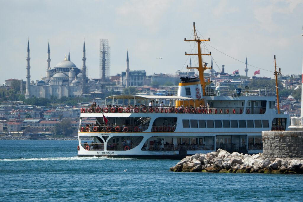 A ferry sails on the Bosphorus with the iconic Sultan Ahmed Mosque in the background, İstanbul, Türkiye.