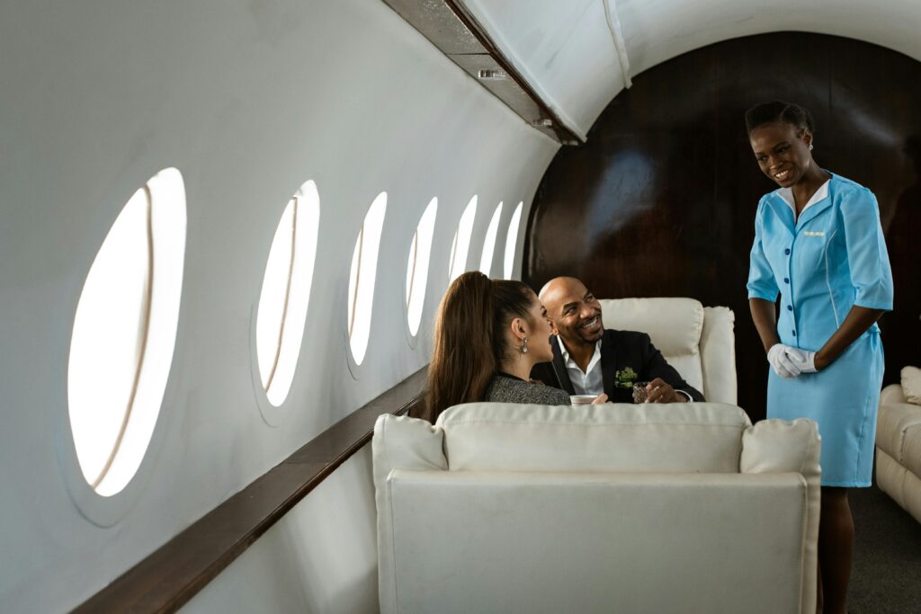 Business people interact with a flight attendant on a private jet, highlighting luxury air travel.
